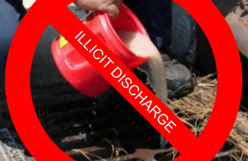 Pouring liquid into a drain, "Illicit Discharge" striked out in red