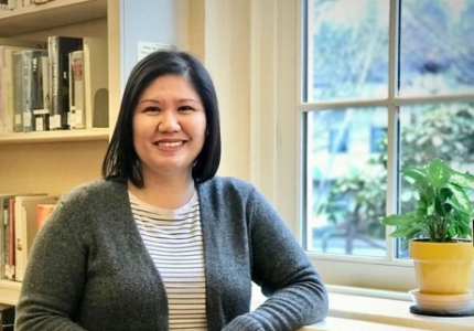 woman standing in front of bookcase with a window in the background