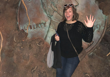 woman standing in front of a largescale penny embedded in a wall