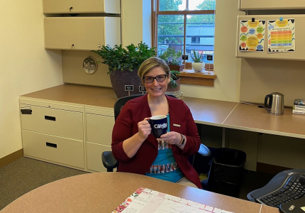 woman holding mug sitting behind a desk