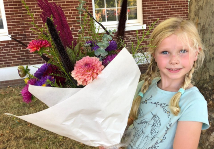 A little girl holding a big bouquet of flowers.