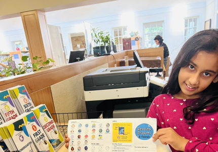 Girl standing next to a counter with Reading Dragon cards laid out.