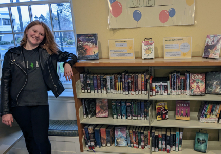 Young woman standing next to bookshelves