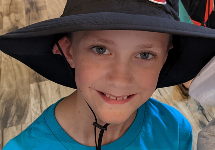 Picture of boy wearing a blue shirt and a Camas hat.