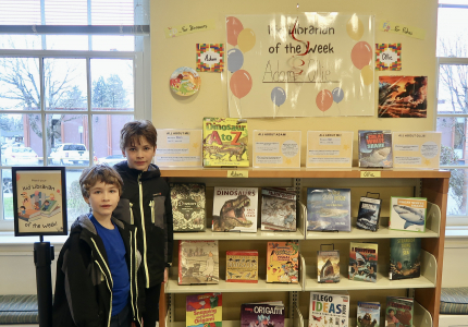 Ollie and Adam standing next to their Kid Librarian display