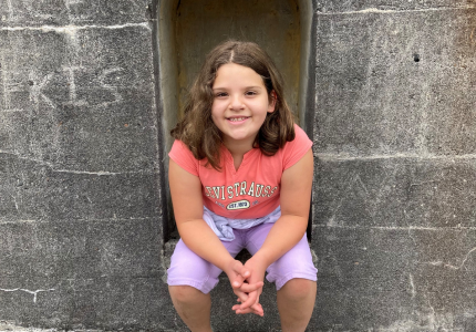 Samantha sitting in an outdoor stone alcove