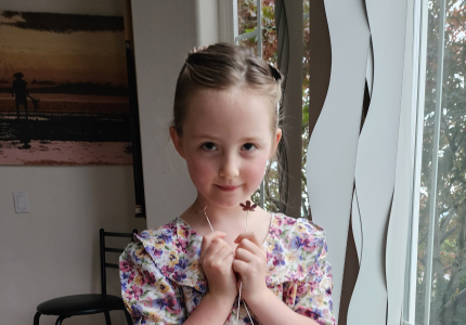 Finley standing next to a window in a flower dress