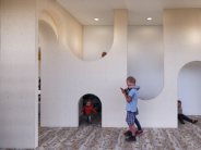 Discovery Hallway with climbing spaces and children exploring curved openings.