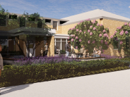 A courtyard at the Camas Public Library features people walking, sitting, and socializing surrounded by purple flowers