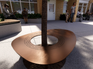 Close-up of a round bench surrounding a tree in the Camas Library courtyard, featuring engraved names on the bench surface