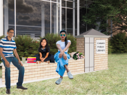 Family sits on monument bench in front of Library.