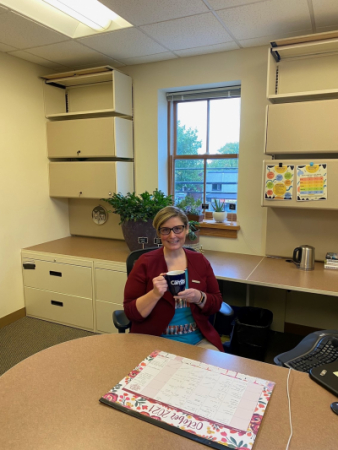 woman holding mug sitting behind a desk