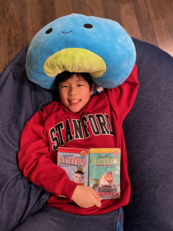 Bryson laying on a bean bag chair with a book and a large squish toy.
