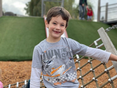 Bowen on a playground smiling next to a play structure.