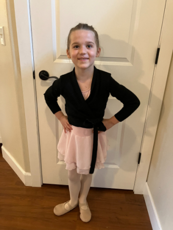 Lily standing in front of a door smiling with her hands on her hips