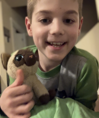 Jackson smiling and holding a toy cat