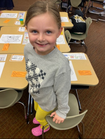 Madelyn standing next to a chair and table