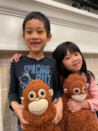 Ethan and Chloe holding toy monkeys with Chloe's hand on Ethan's shoulder